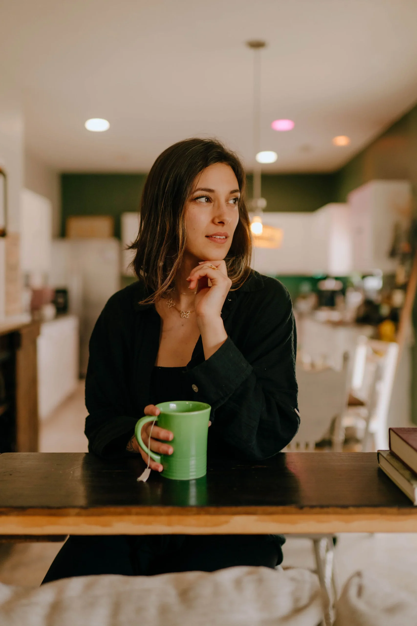 image of a girl wearing all black and holding a green teacup in her kitchen