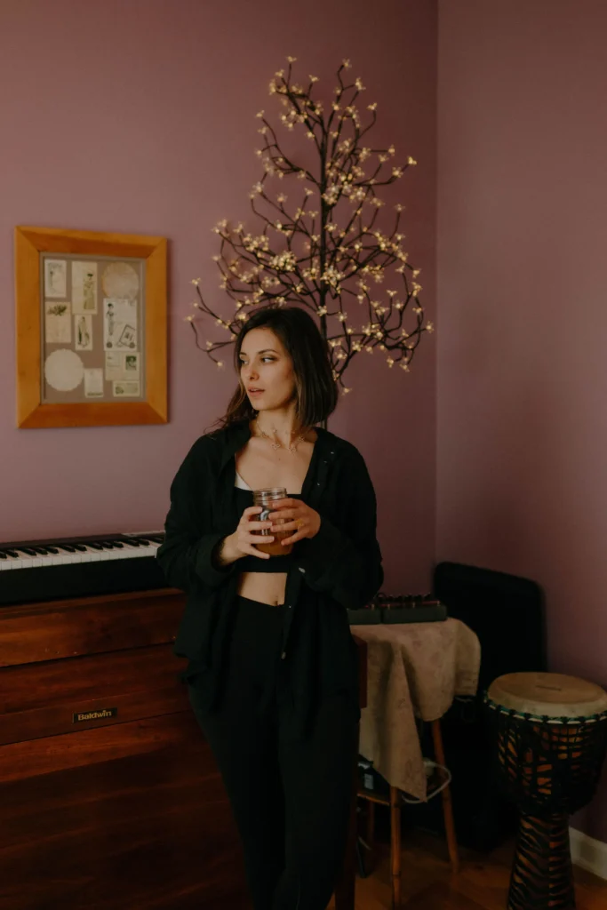 woman at a piano wearing all black in a purple room looking to the side