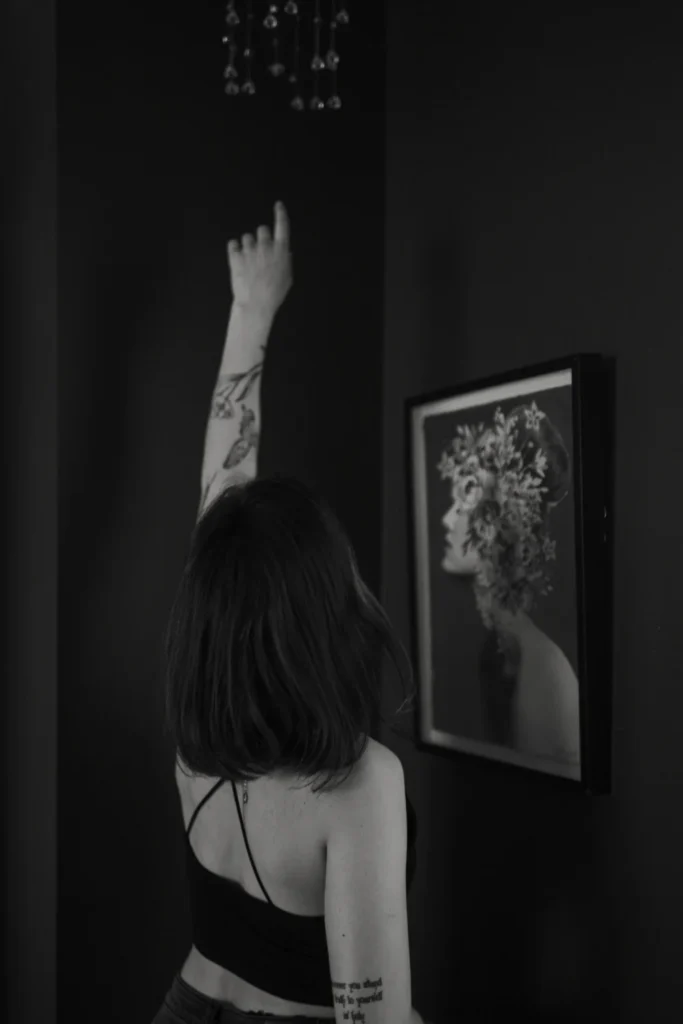 black and white image of a girl reaching up to a hanging ornament in her room